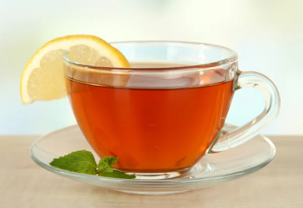 Tasse Tee mit Zitrone auf dem Tisch auf hellem Hintergrund — Stockfoto