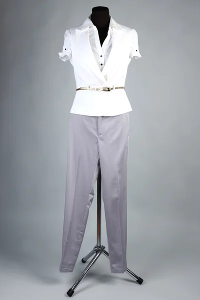Bonita blusa, chaqueta blanca y pantalones grises en maniquí, sobre fondo gris —  Fotos de Stock