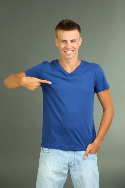 T-Shirt auf jungem Mann, auf grauem Hintergrund — Stockfoto