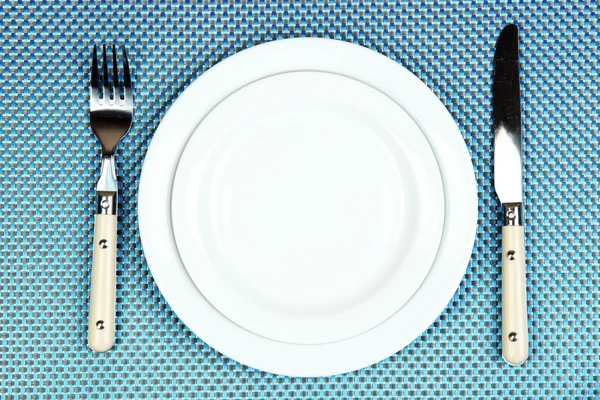 Cuchillo, placa de color y tenedor, sobre fondo de color — Foto de Stock