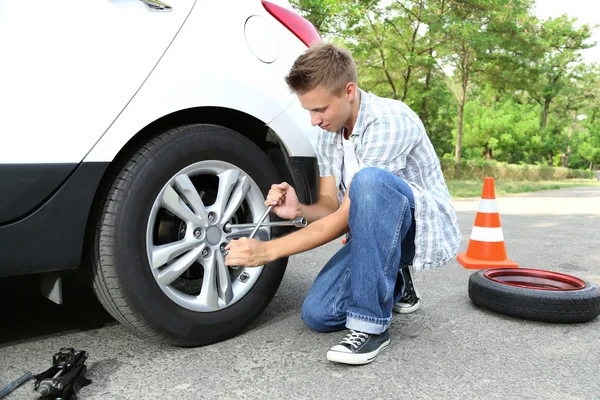 Man driver having trouble at road changing wheel Stock Image