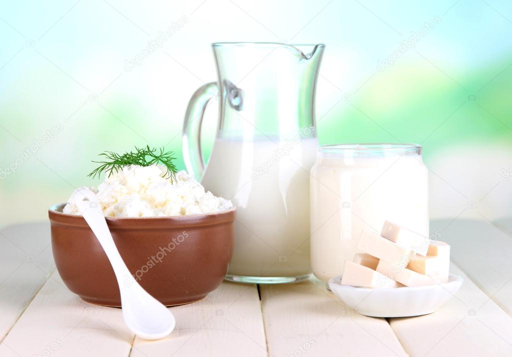 Fresh dairy products on wooden table on natural background