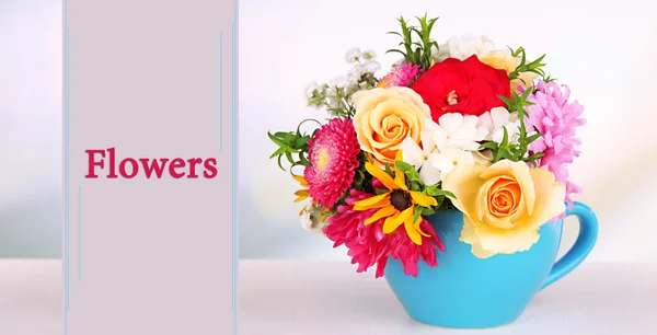 Mooi boeket van heldere bloemen in blauwe mok op lichte achtergrond — Stockfoto
