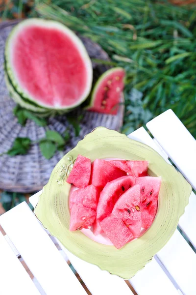 Watermelon slices on plate on table on grass background — Stock Photo, Image