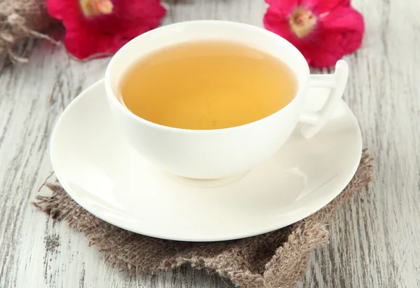 Kopp med te og rosa mallow blomster på trebakgrunn – stockfoto