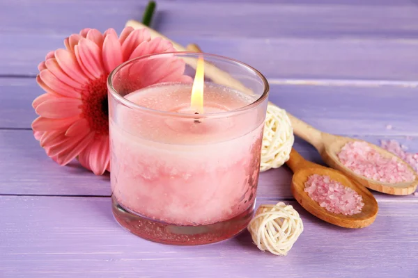 Beautiful pink candle with flower on purple wooden background — Stock Photo, Image