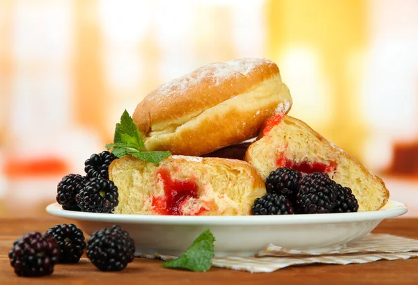 Tasty donuts with berries on wooden table — Stock Photo, Image