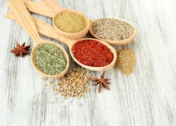 Assortment of spices in wooden spoons on wooden background — Stock Photo, Image