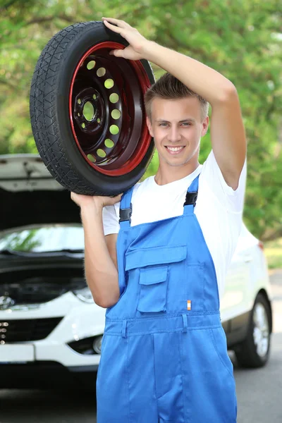 Auto mechanic with tire on his shoulder — Stock Photo, Image