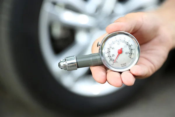 Hand som håller manometer för bil däck mätning — Stockfoto