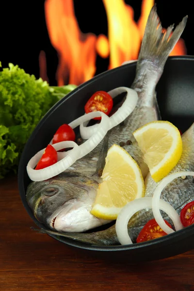 Dorado pescado en la mesa en el fondo de fuego —  Fotos de Stock