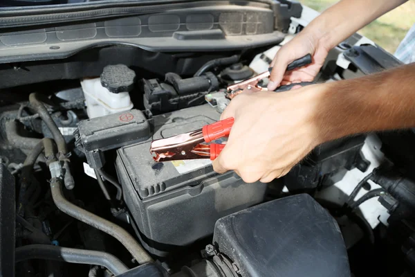 Car mechanic uses battery jumper cables to charge dead battery — Stock Photo, Image