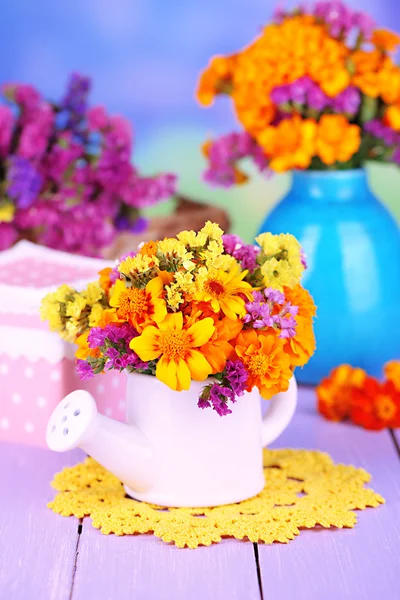 Bouquet of marigold flowers in watering can on wooden table on natural background — Stock Photo, Image