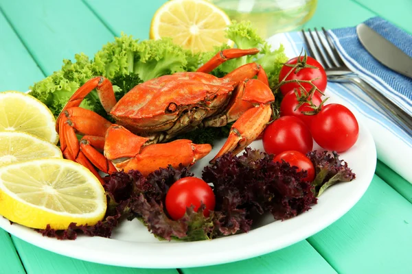 Crabe bouilli sur assiette blanche avec feuilles de salade et tomates, sur fond de table en bois — Photo