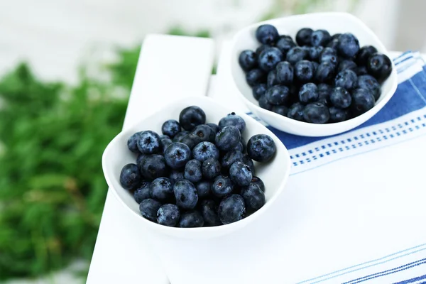 Blåbär i plattor på servett på träbord på gräs bakgrund — Stockfoto