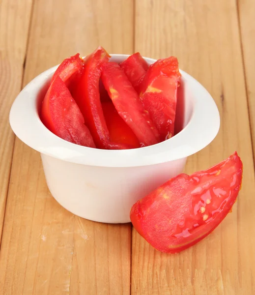 Jasne świeżych pomidorów pokrojone plastry w misce na drewniany stół szczegół — Zdjęcie stockowe