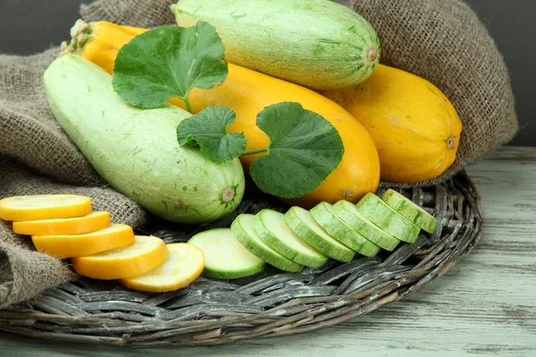 Gesneden en hele rauwe courgette op jute achtergrond — Stockfoto