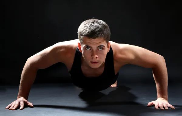 Pohledný mladý svalnatý sportovec, na tmavém pozadí — Stock fotografie