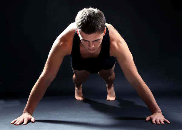 Schöner junger muskulöser Sportler, auf dunklem Hintergrund — Stockfoto