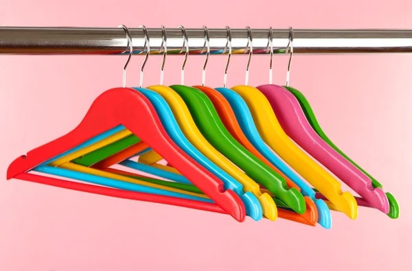 Kleurrijke kleerhangers op roze achtergrond — Stockfoto