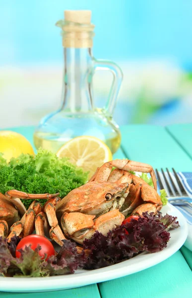 Вареные крабы на белой тарелке с листьями салата и помидорами, на деревянном столе, на ярком фоне — стоковое фото