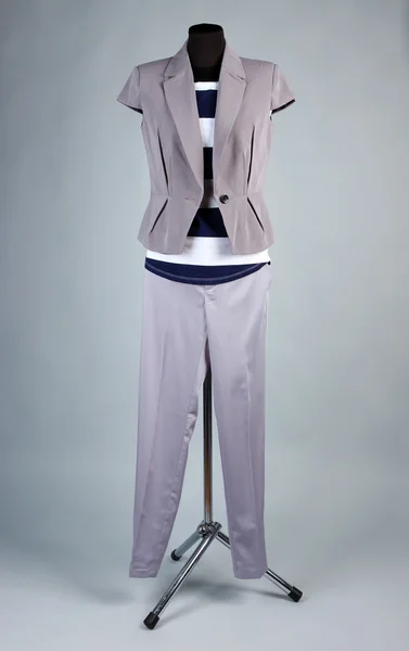 Bella camicetta, giacca e pantaloni grigi su manichino, su sfondo grigio — Foto Stock