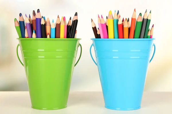 Color buckets with multicolor pencils, on color background — Stock Photo, Image