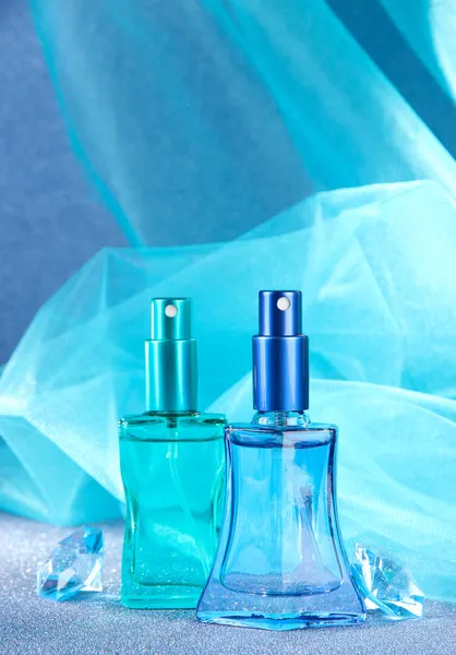 Ženy parfémy v krásných lahvích na modrém pozadí — Stock fotografie