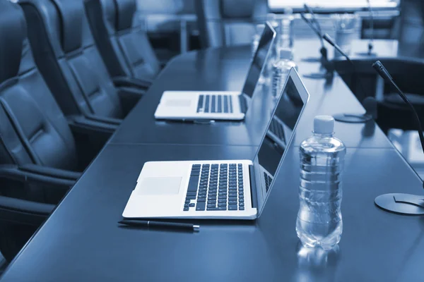 Sala de conferencias vacía con ordenadores portátiles en la mesa en tonos de gris — Foto de Stock