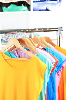 çeşitli ahşap askı raf arka plan üzerinde rahat t-shirt
