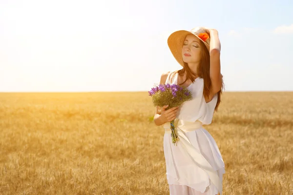 Porträtt av vacker ung kvinna med blommor i fältet — Stockfoto