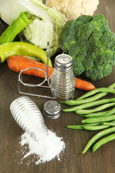 Samenstelling van zout en peper molens en verse groenten, op houten achtergrond — Stockfoto