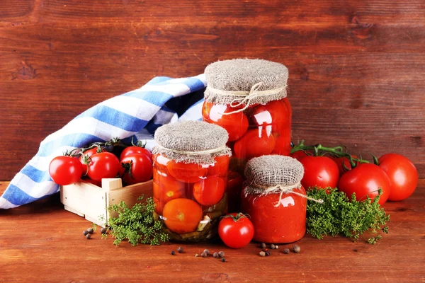 Sabrosos tomates enlatados y frescos sobre mesa de madera —  Fotos de Stock