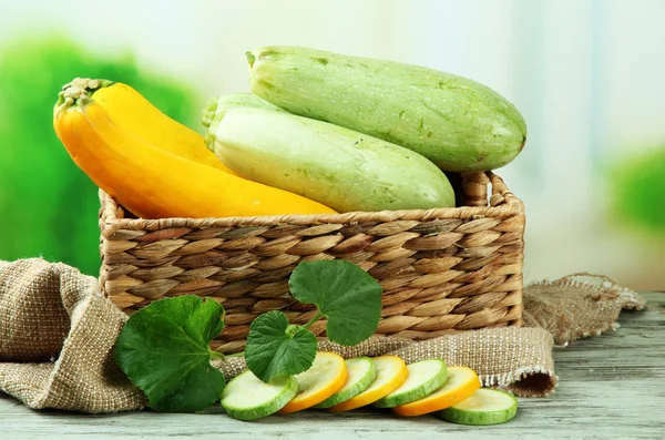 Sliced and whole raw zucchini in wicker crate, outdoors — Stock Photo, Image