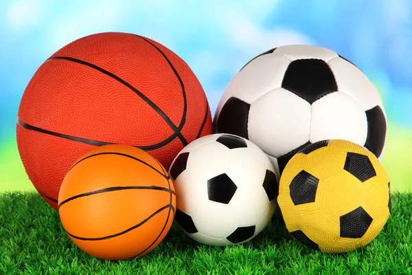 Piłki sportowe, na zielonej trawie, na jasnym tle — Zdjęcie stockowe