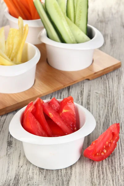 Légumes frais brillants coupés en tranches dans des bols sur une table en bois close-up — Photo