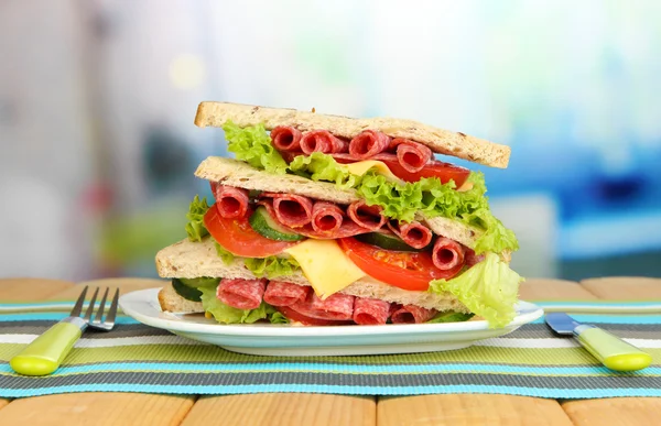 Huge sandwich on wooden table, on bright background — Stock Photo, Image