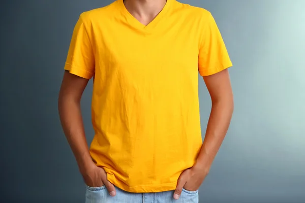 T-Shirt auf jungem Mann, auf grauem Hintergrund — Stockfoto