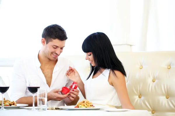 Man proposing and holding up an engagement ring his woman over restaurant table — Stock Photo, Image