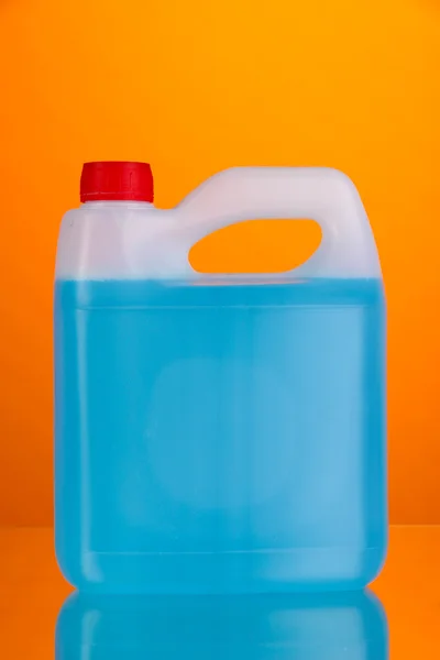 Голубая жидкость для автомобиля в канистре на оранжевом фоне — стоковое фото