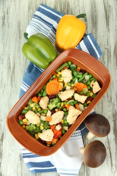 Cacerola con verduras y carne, sobre fondo de madera — Foto de Stock