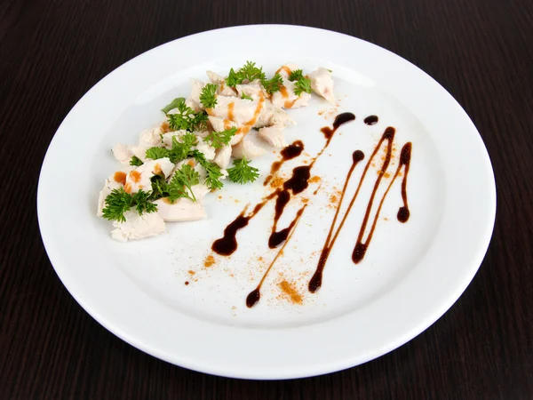 Gehakte gekookte kippenvlees met saus, op witte plaat, op houten achtergrond en paprika, — Stockfoto