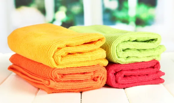 Colorful towels on wooden table on window background — Stock Photo, Image