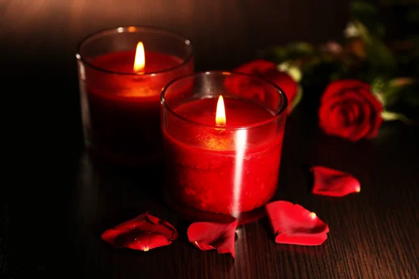 Hermosas velas rojas románticas con pétalos de flores sobre fondo de madera oscura — Foto de Stock
