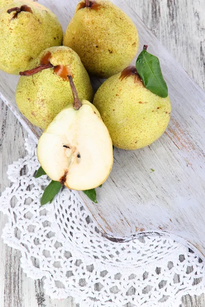 Pears on board on napkin on wooden background — Stock Photo, Image