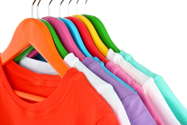 Camisas diferentes em cabides coloridos no fundo branco — Fotografia de Stock