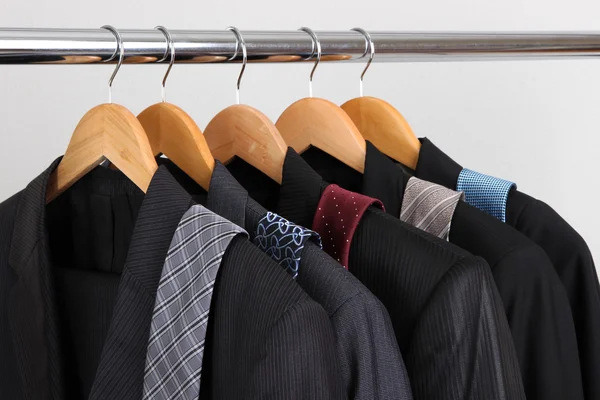 Ternos e gravatas em cabides no fundo cinza — Fotografia de Stock