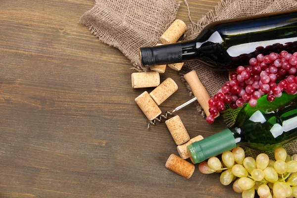 Bottiglie di vino, uva e tappi su fondo di legno — Foto Stock