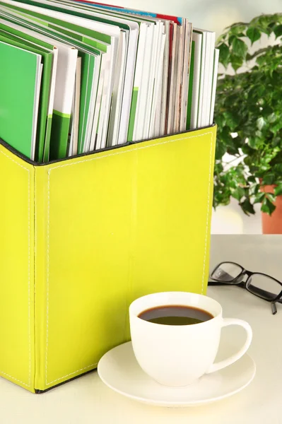 Revistas y carpetas en caja verde, sobre fondo interior de oficina — Foto de Stock