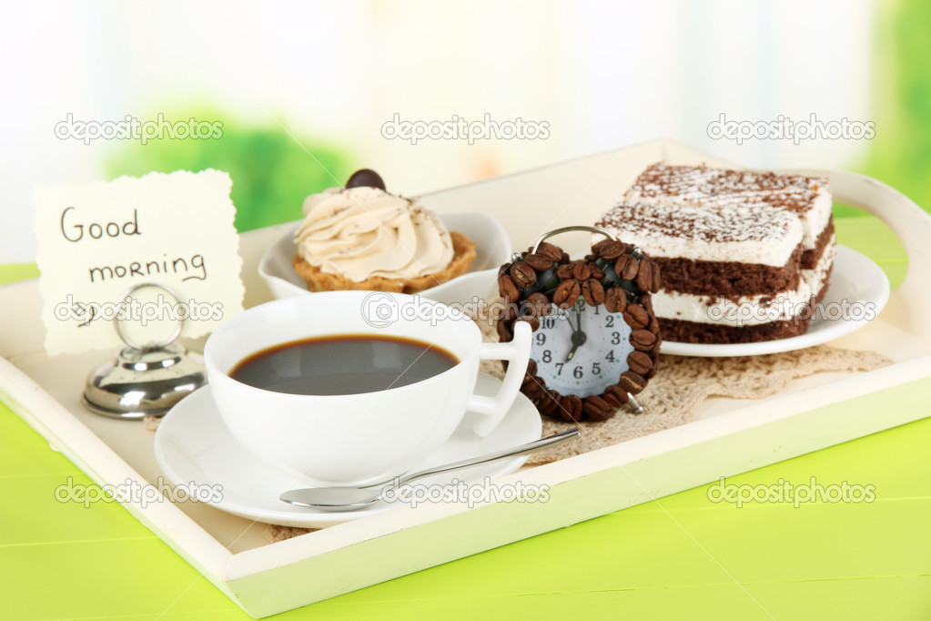 Cup of tea with cakes on wooden tray on table in room